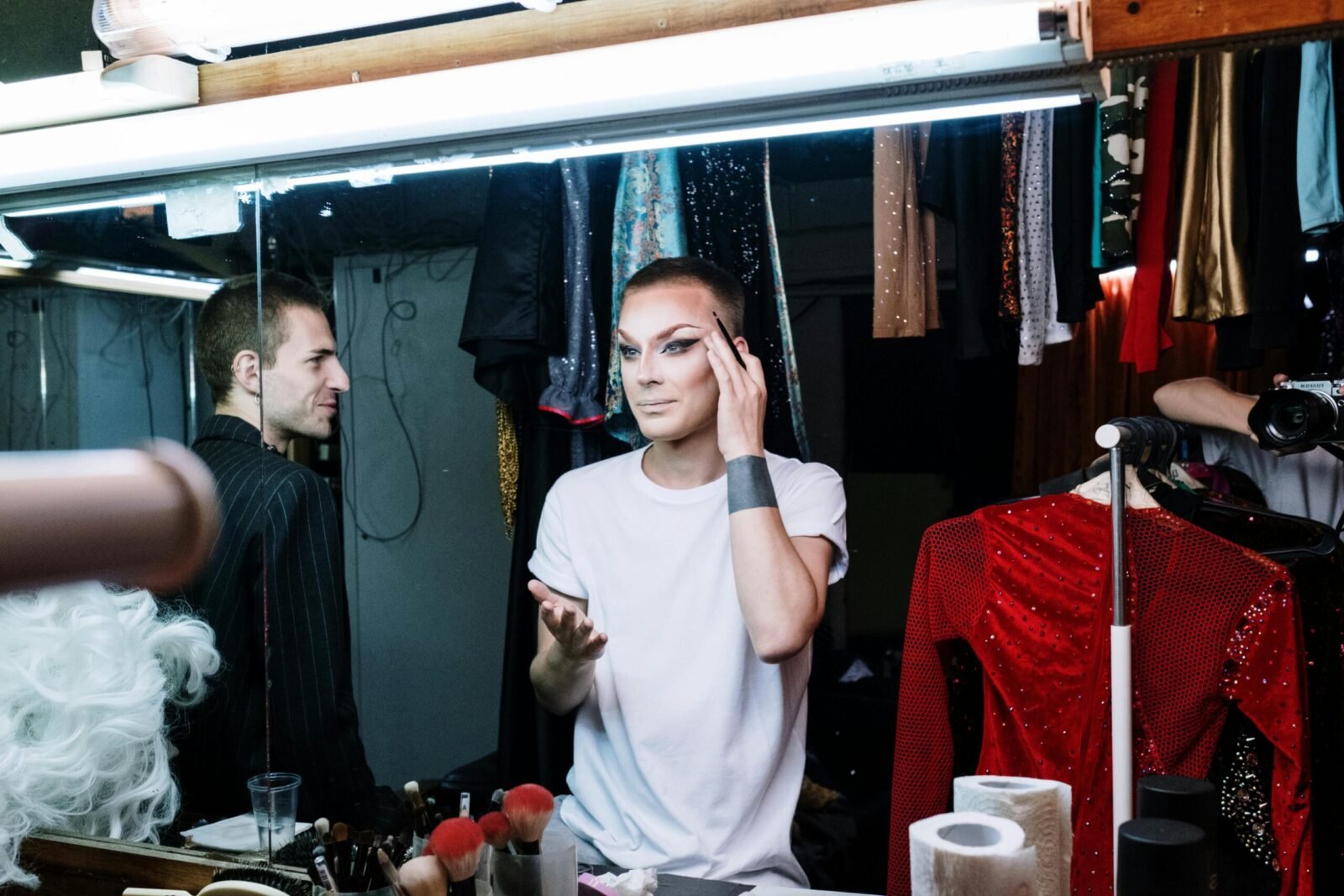 A drag queen applying makeup backstage, showcasing transformation and self-expression.